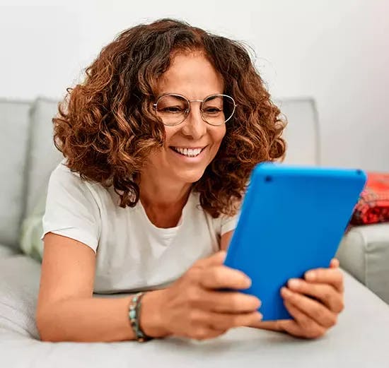 Mulher feliz olhando para um tablet que está em suas mãos